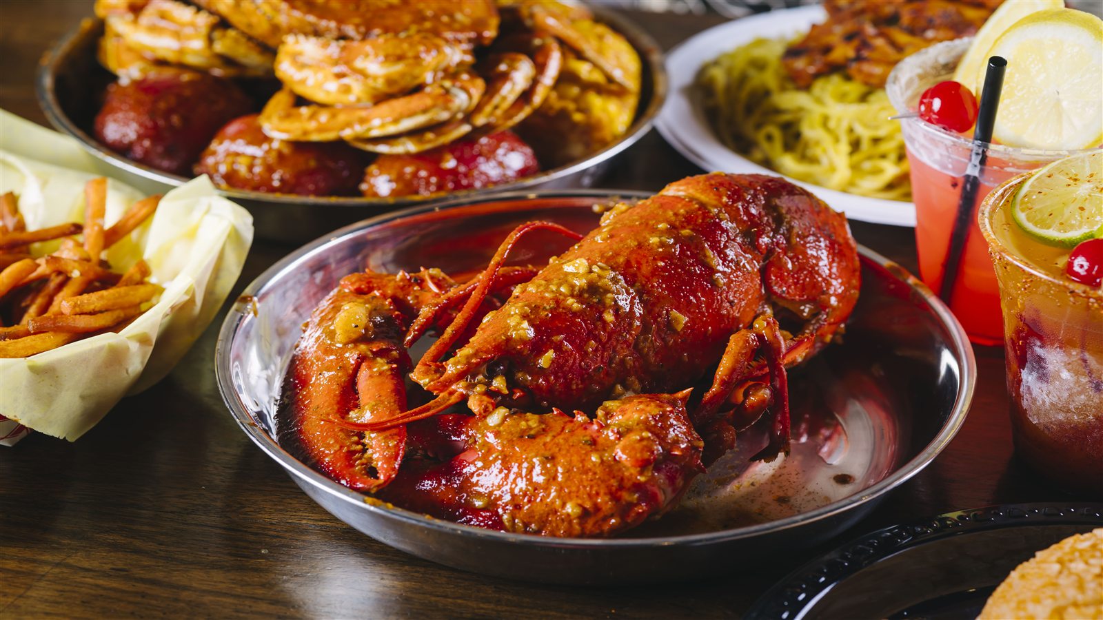 Saucy lobster seafood boil served with colorful drinks